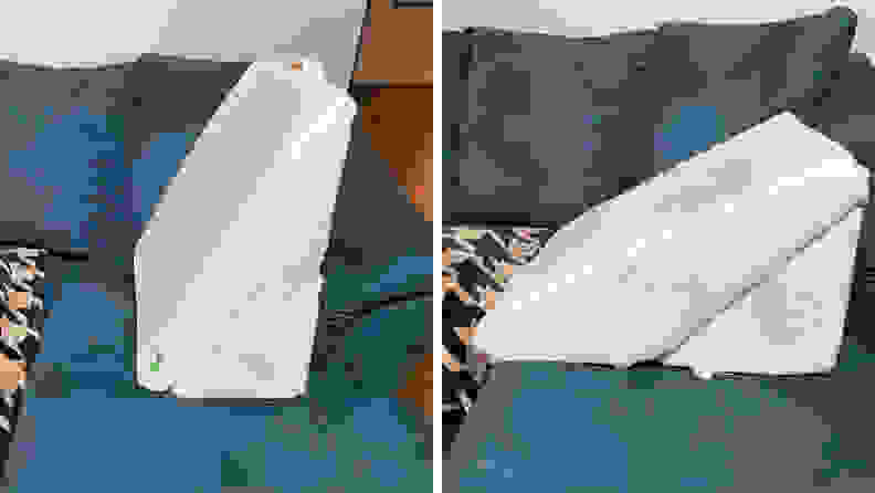 A Cushy Form Wedge Triangle Pillow upright and horizontal on blue suede couch.