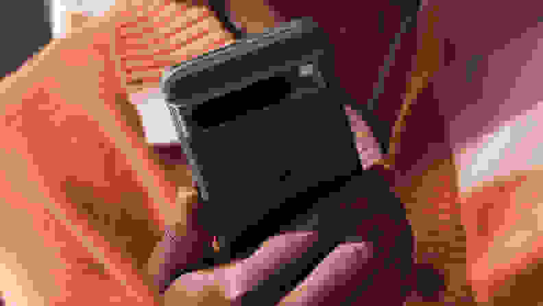 An individual holds a black Google Pixel 8 Pro smartphone. The camera array on the backside of the handset is visible.