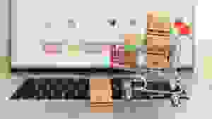 A miniature shopping cart sits on the keyboard of a laptop