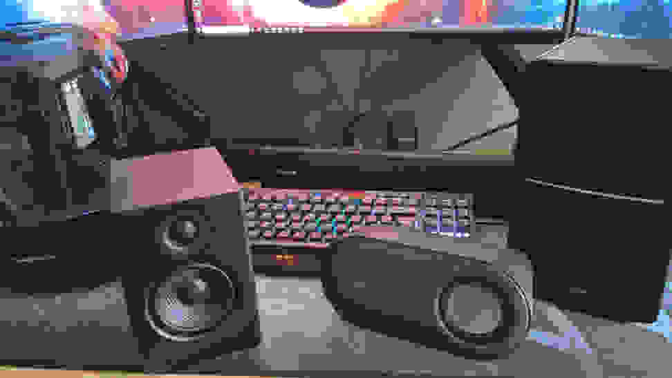 A pair of PC speakers on a desk with a monitor in front