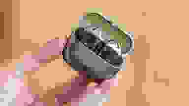 A hand holding up an open case with the earbuds inside.