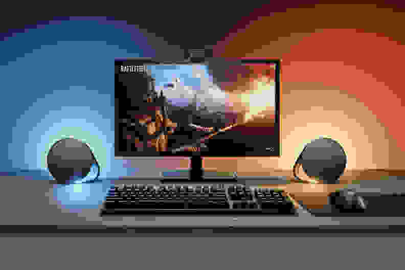 A pair of logitech g560, one of the best computer speakers, next to a monitor