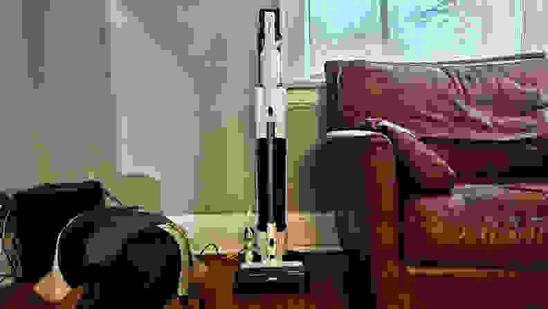 The Tineco Pure One Station 5 stands in a living room next to a big leather arm chair