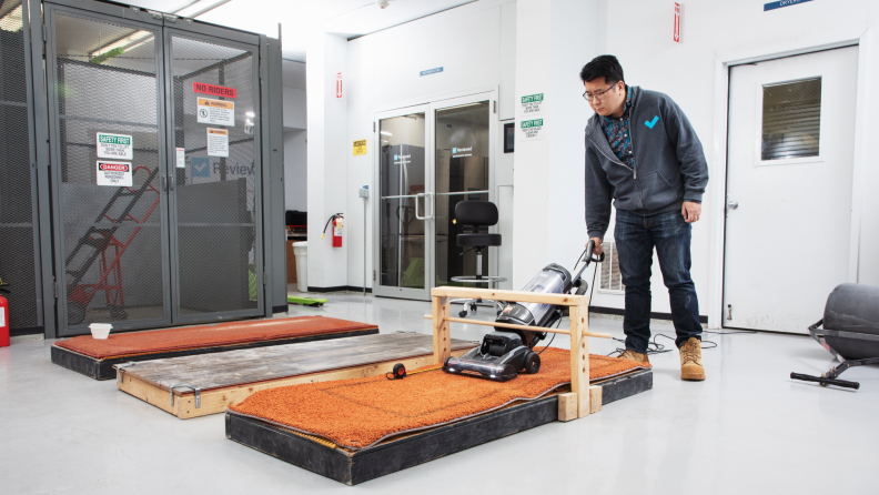 A person in a lab vacuuming a carpeted surface as part of testing the best cordless vacuums